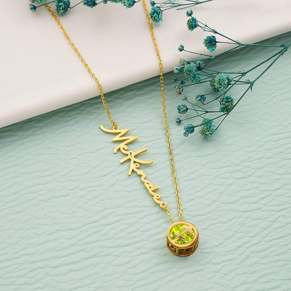 A gold cable chain necklace with a round Sagittarius birthstone pendant, displaying a name engraved on the chain