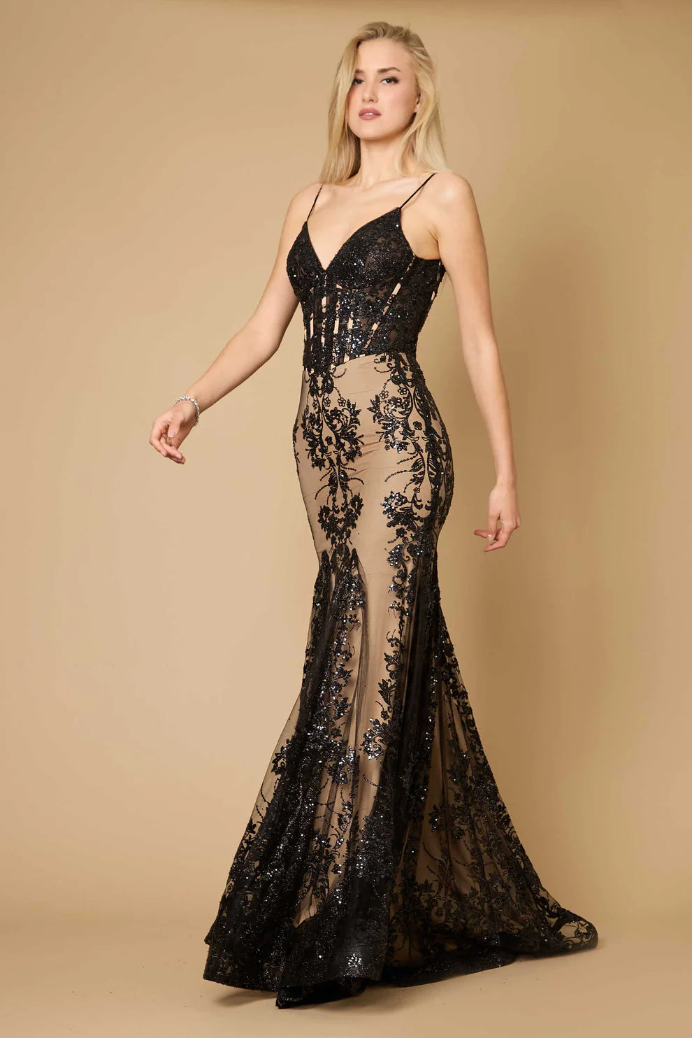 Woman wearing a black and beige lace evening gown on a tan background