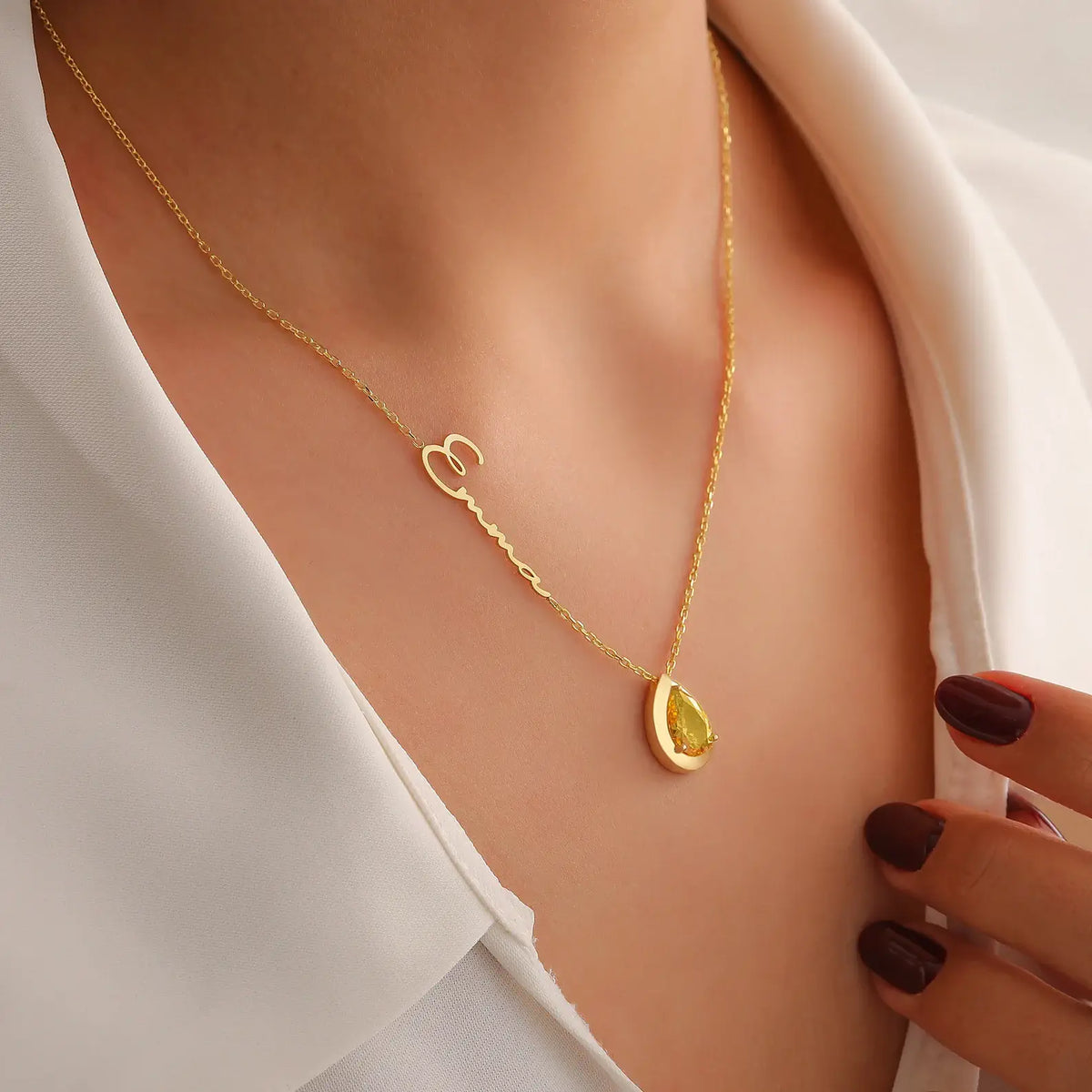 Gold necklace with a citrine gemstone pendant on a woman wearing a white top.