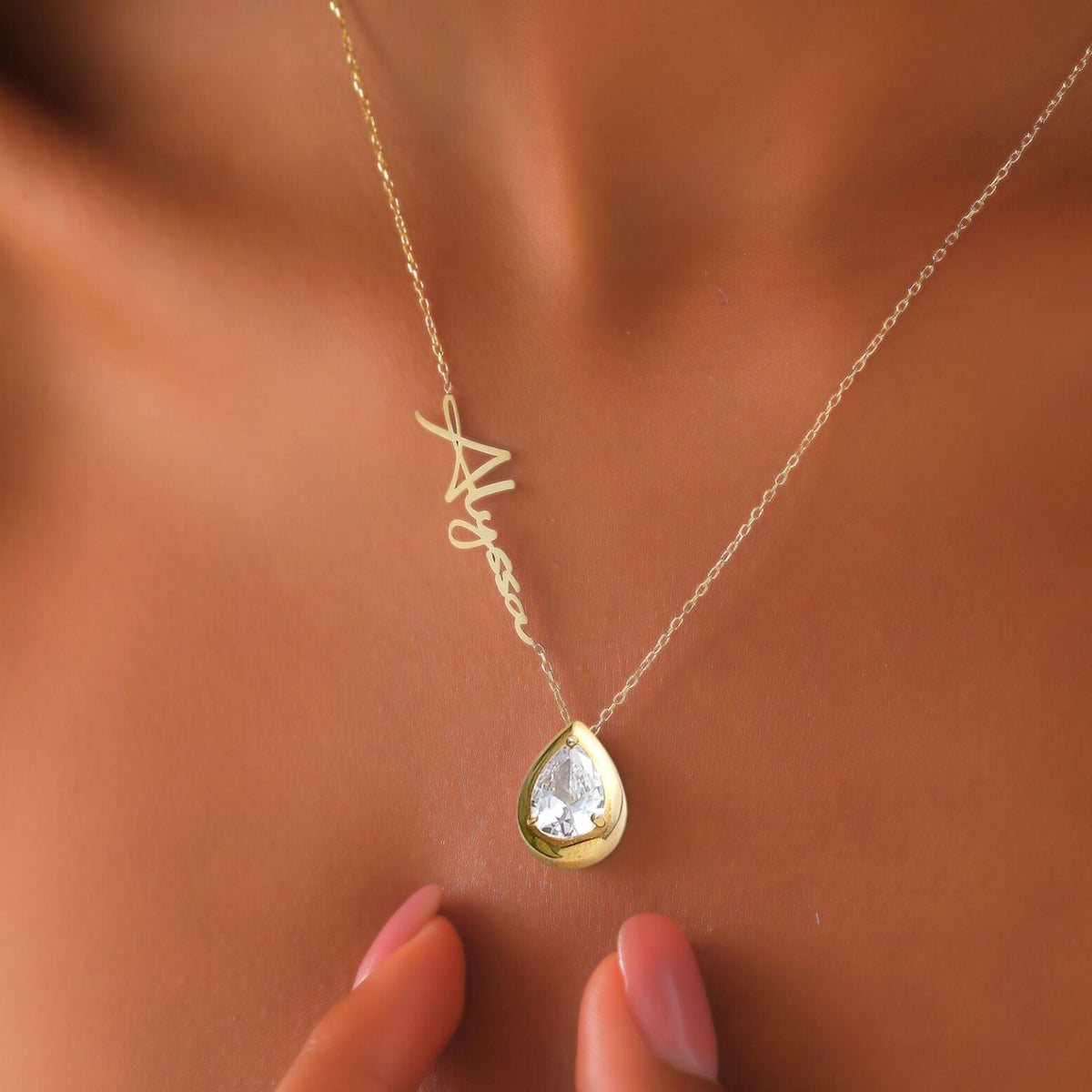 Gold necklace with a teardrop diamond pendant on a woman's neck