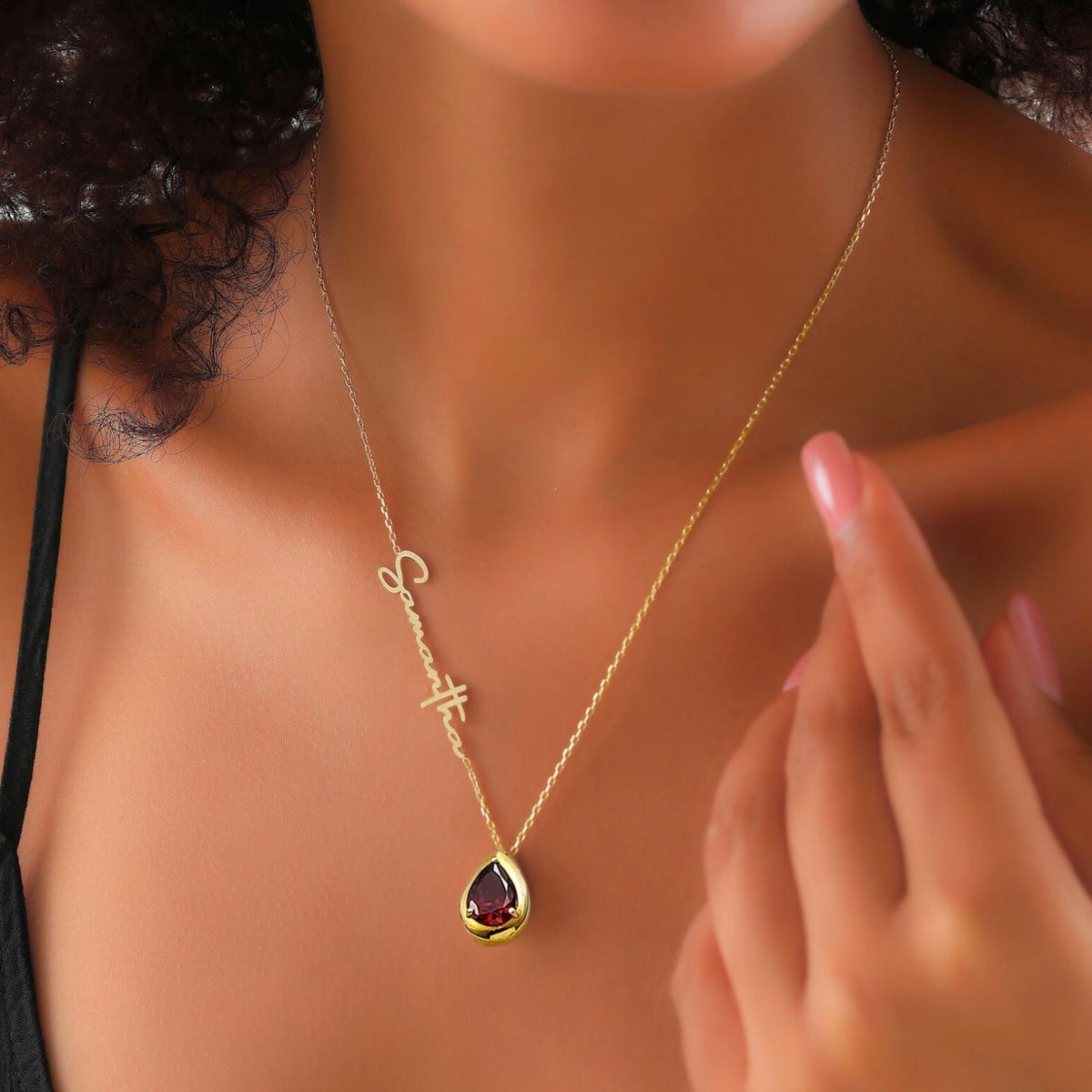 Gold necklace with a teardrop garnet pendant worn by a lady
