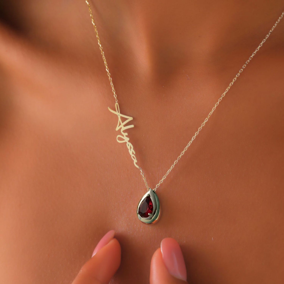 Silver necklace with a teardrop-shaped garnet pendant on a woman's neck
