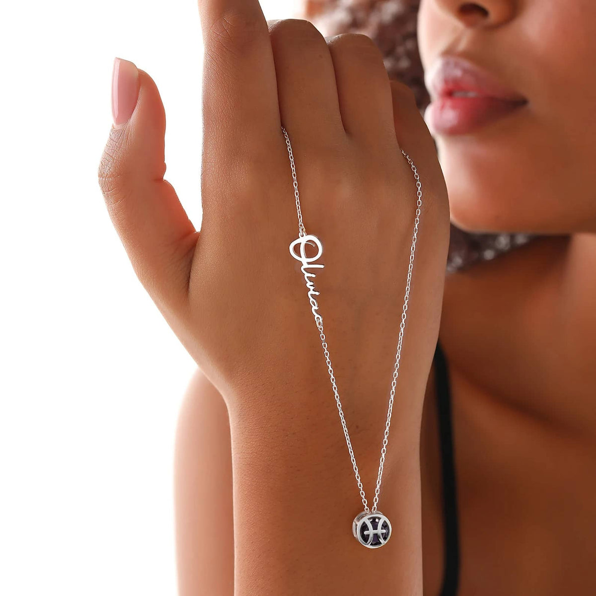 A close-up image of a Pisces Birthstone Necklace showing a silver pendant with the symbol for Pisces and an engraved name.