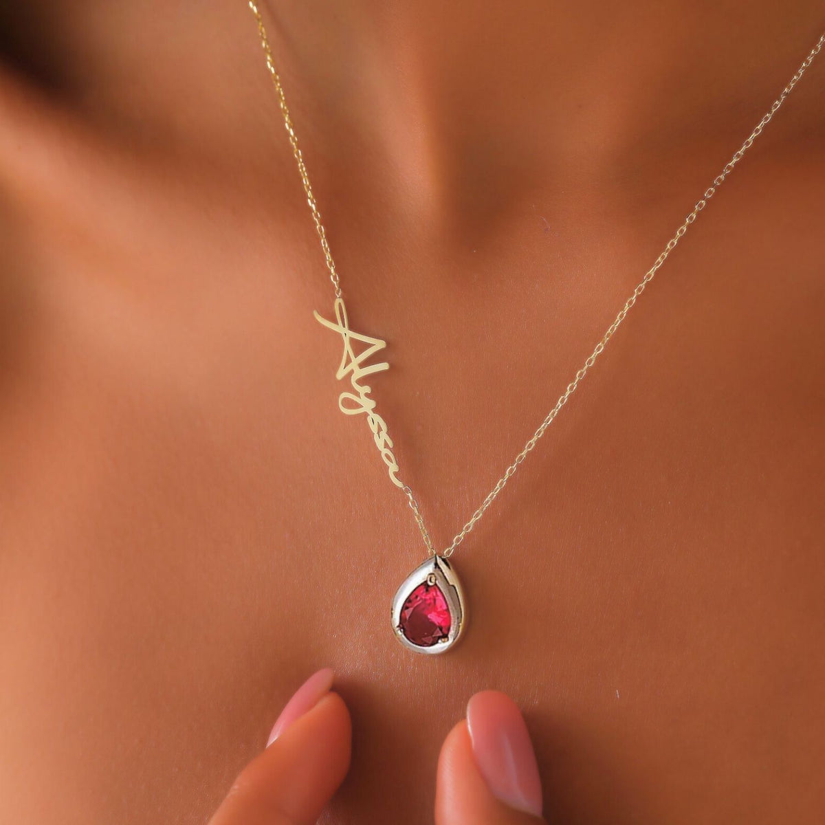Necklace with a teardrop-shaped ruby gemstone pendant on a woman's neck.