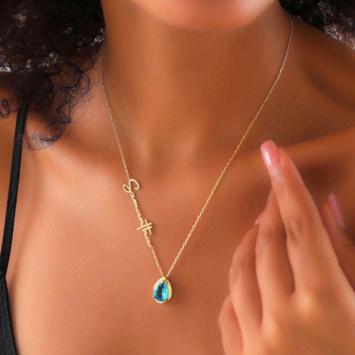 Gold necklace with a blue topaz pendant worn by a woman