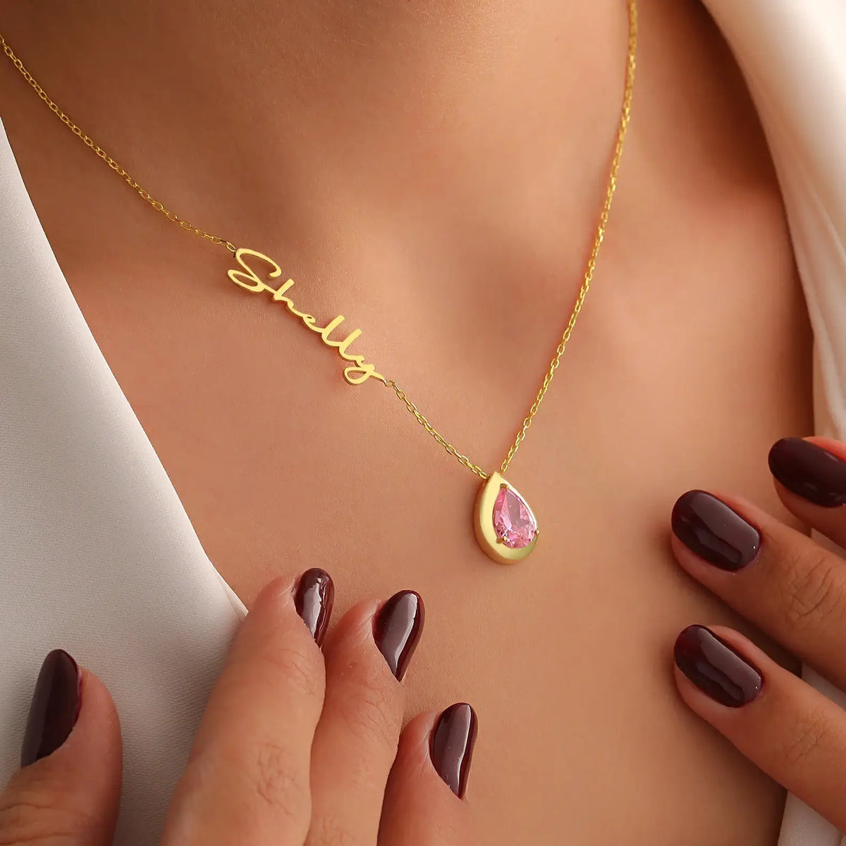 Gold necklace with a pink tourmaline teardrop pendant on a woman's neck