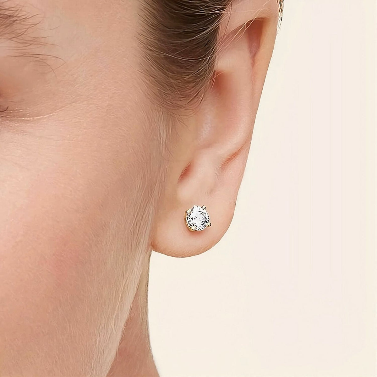 Close-up of a diamond earring on an ear with a soft background