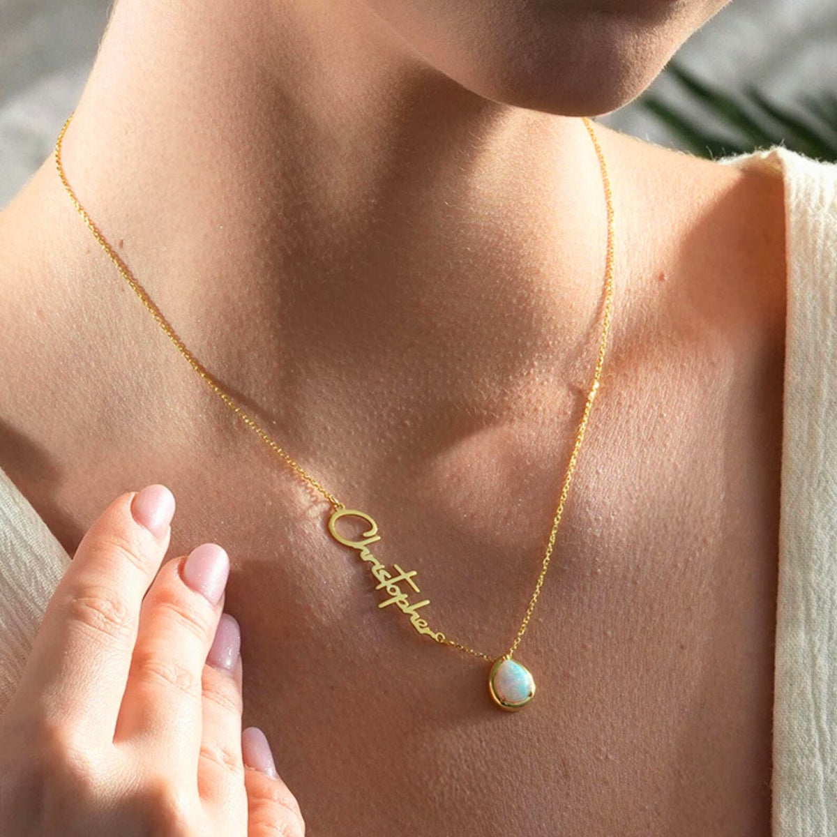 Gold opal necklace with a nameplate on a person's neck