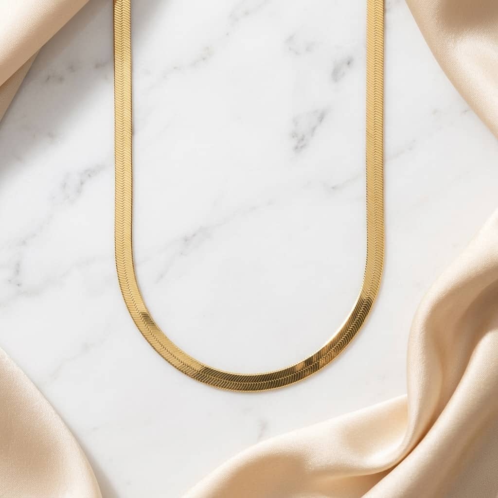 Close up flat lay of a thick, woven yellow gold herringbone chain necklace