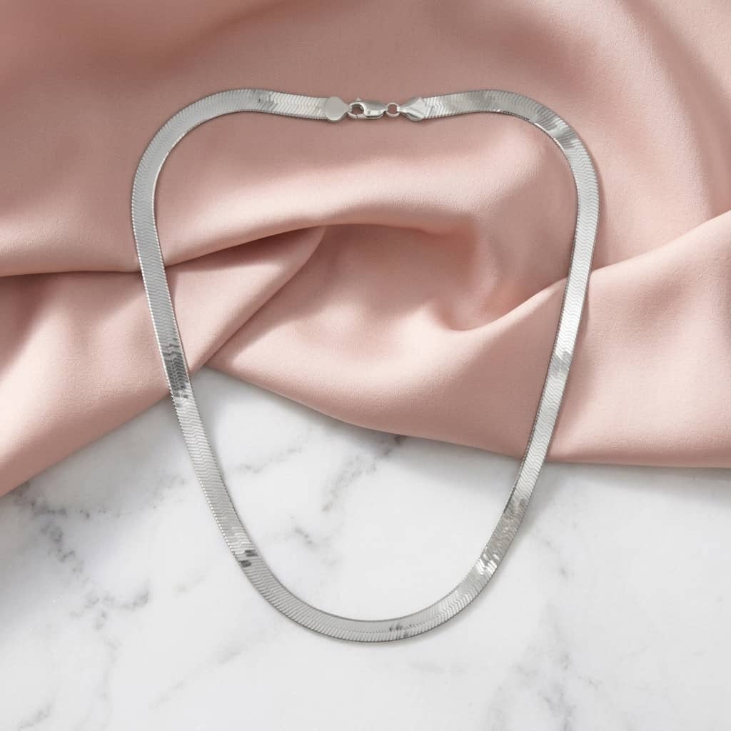 Full length flat lay of a silver herringbone necklace