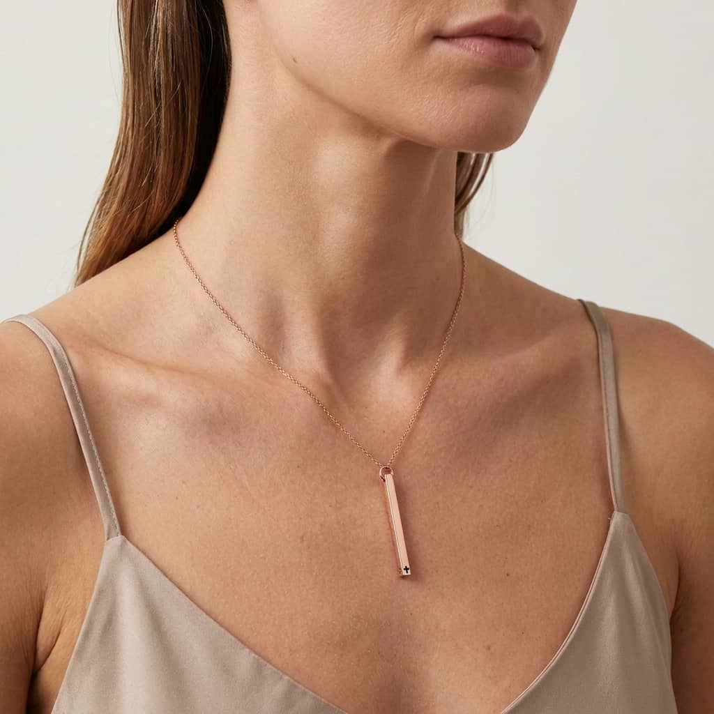 Woman wearing a delicate rose gold necklace with a minimalistic bar pendant on a neutral background