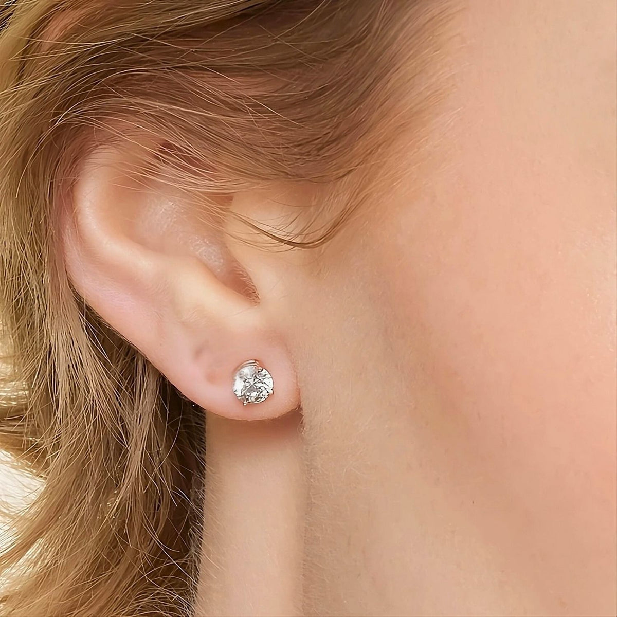 Close-up of an ear wearing a gold diamond stud earring