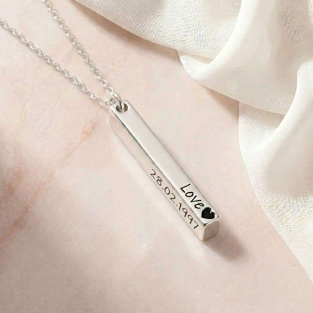 Silver necklace with a bar pendant on a light fabric background