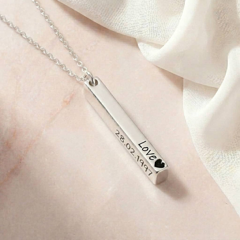 Silver necklace with a bar pendant on a light fabric background