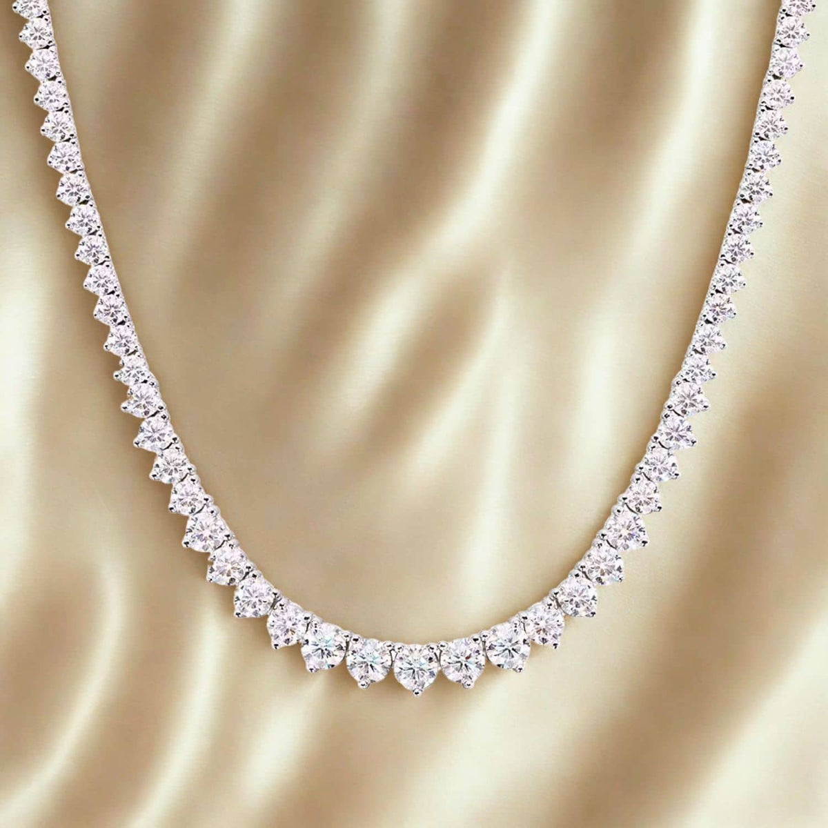 Diamond tennis necklace on a gold fabric background